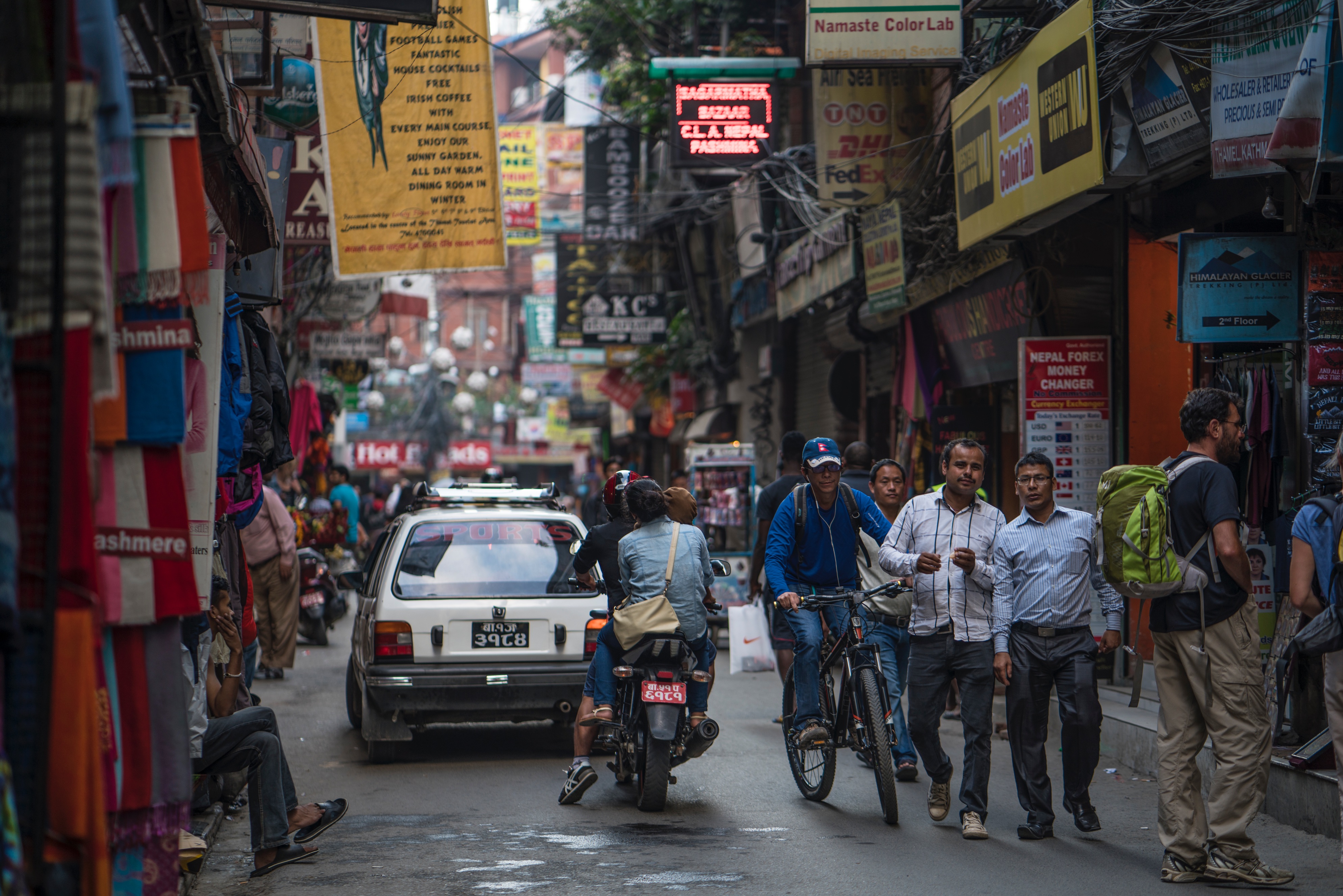 Narrow street in Nepal with shops, people and vehicles