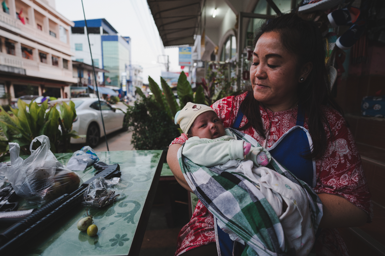 South-East Asian lady holding a baby in a shop front